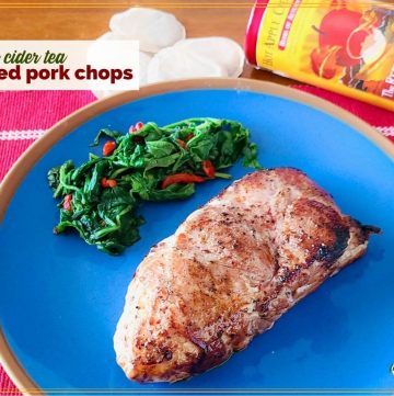 pork chop on a plate with greens and text overlay "apple cider tea rubbed pork chops"