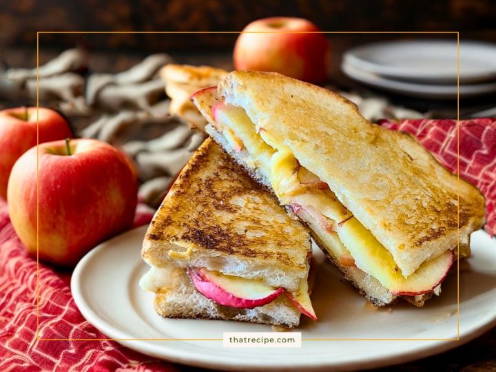grilled cheese sandwich on a plate with apples in the background