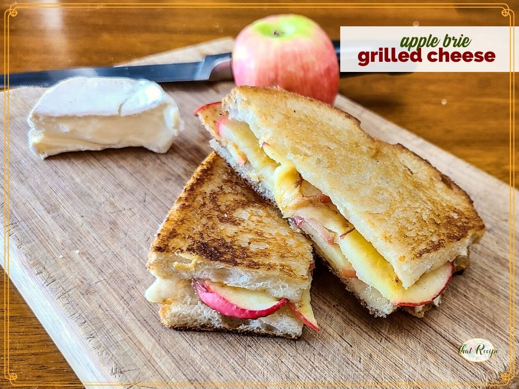 grilled cheese sandwich on cutting board with brie and apple and text overlay "apple brie grilled cheese sandwich"