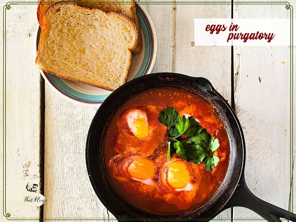 cast iron skillet with eggs in tomato sauce and text overlay "eggs in purgatory"