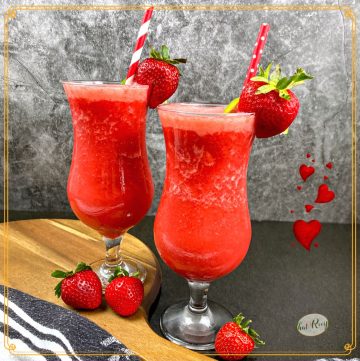2 strawberry daiquiris in hurricane glasses with fresh strawberries