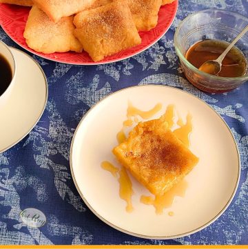sopaipillas on a plate with cinnamon sugar and honey