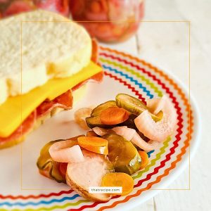 mixed pickles on a plate with a sandwich