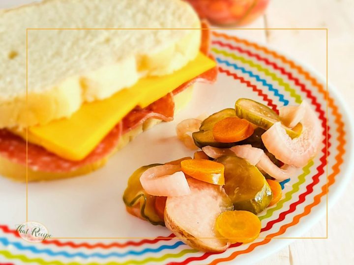 mixed pickles on a plate with a sandwich