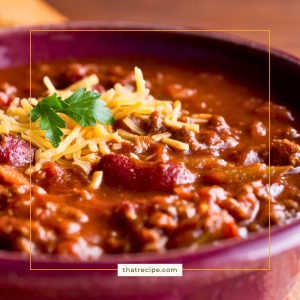 close up of a bowl of chili with beans. topped with cheese.