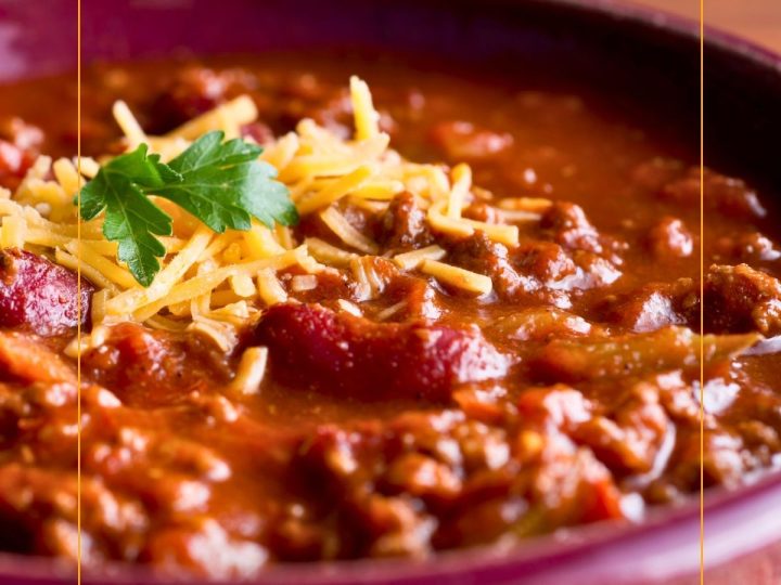 close up of a bowl of chili with beans. topped with cheese.