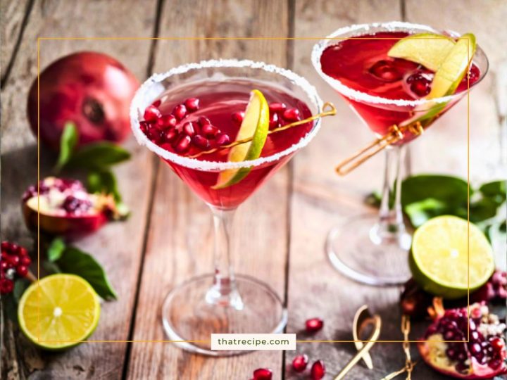 Pomegranate Martinis on a table with fresh pomegranates and limes