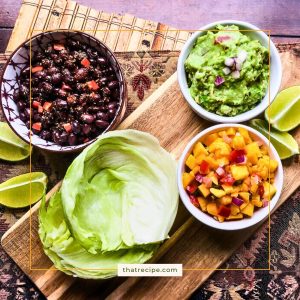 bowls of black beans, guacamole and mango salsa with lettuce leaves