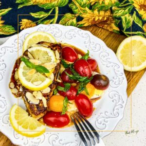 seared white fish with lemon and caprese salad on a plate