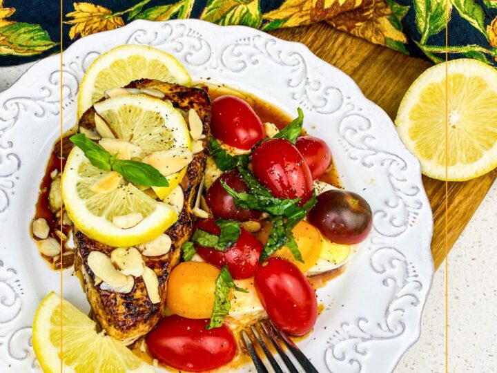seared white fish with lemon and caprese salad on a plate