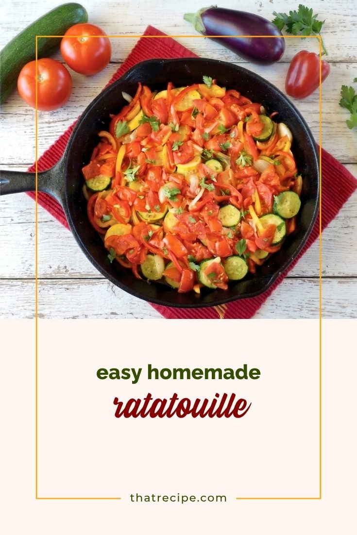 top down view of ratatouille in a skillet with fresh vegetables on a table around it.
