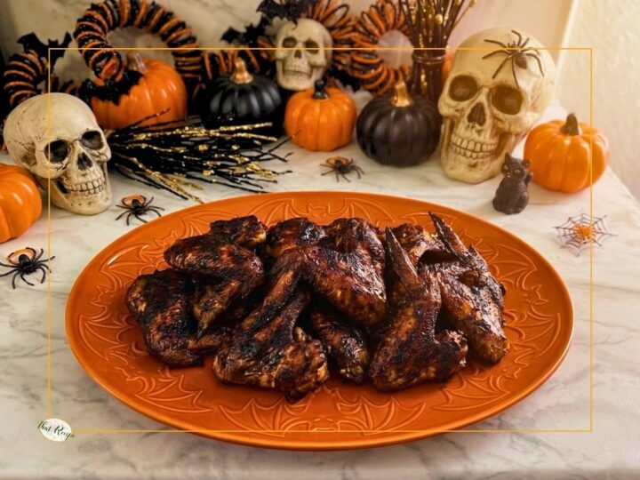 chicken wings with a black sauce on a plate with Halloween decor